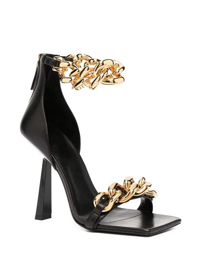 Black high-heeled sandal with gold chain design on a white background