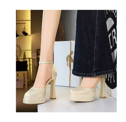 Beige high-heeled shoes worn with a black skirt and white top.