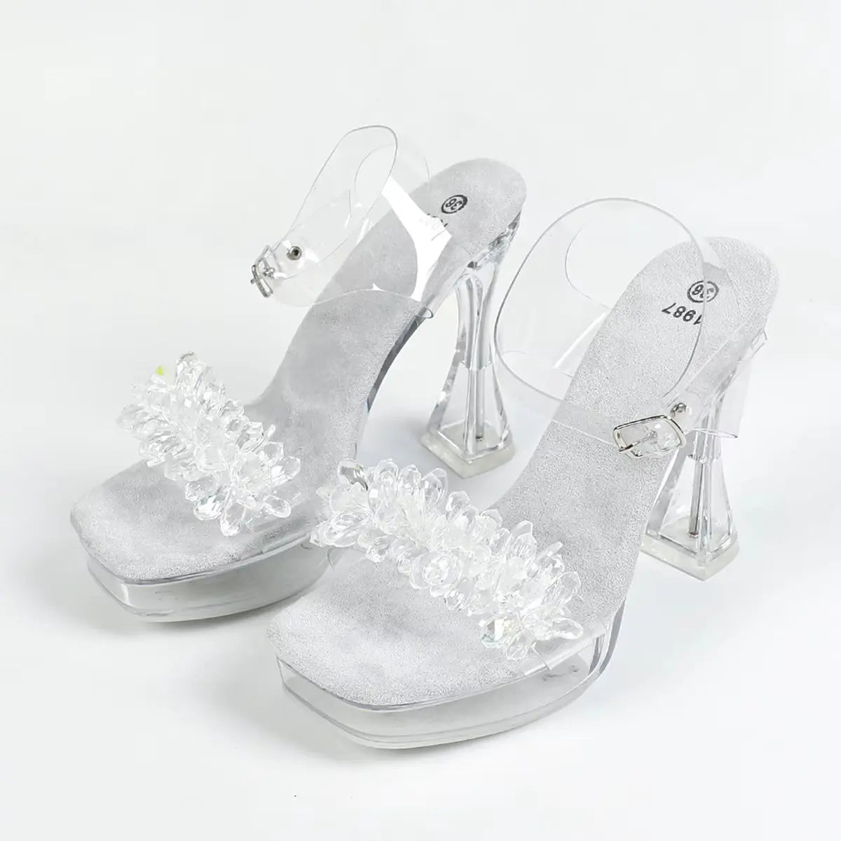 Clear high-heeled shoes with decorative elements on a white background