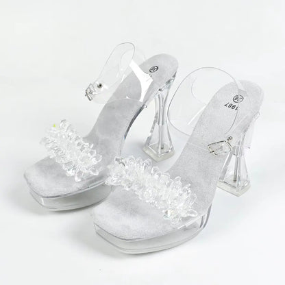 Clear high-heeled shoes with decorative elements on a white background