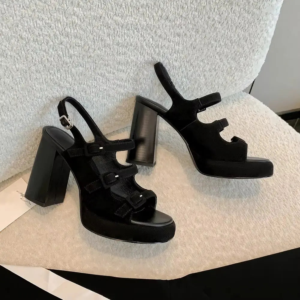Black high-heeled sandals on a textured surface