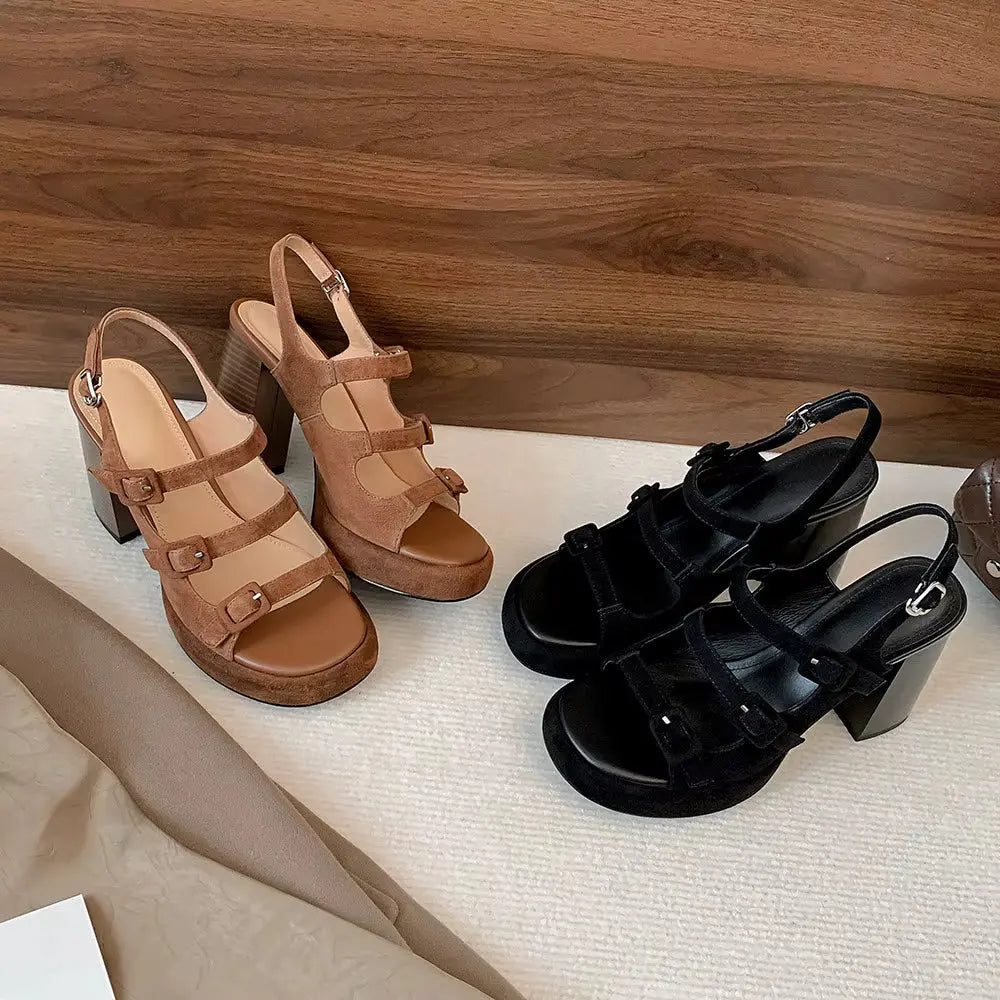 Pair of brown sandals and black sandals on a textured surface with a wooden background