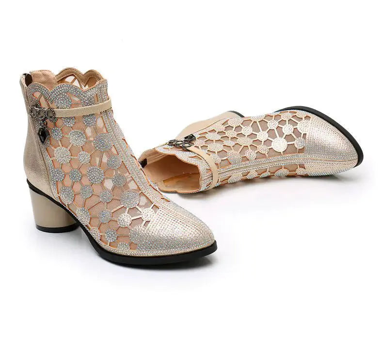 Pair of beige open-toe shoes with floral lace design on a white background